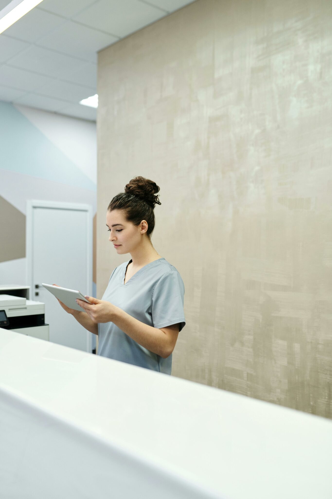 Professional receptionist in uniform using a tablet in a modern office setting.